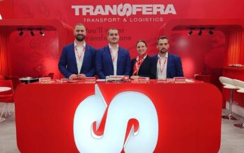 Transfera team at the Transport Logistic trade fair in Munich, standing at the company’s red exhibition booth and presenting logistics solutions.