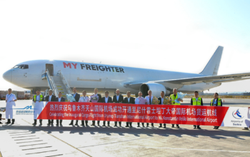 Officials and partners stand on the airport runway in front of a My Freighter cargo aircraft, holding a banner celebrating the inaugural cargo flight between Urumqi Tianshan International Airport and Niš Constantine the Great Airport.