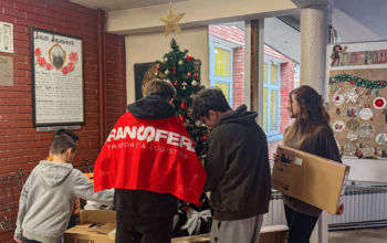 Transfera representatives donate technical equipment to children at the Zvečanska Center in Belgrade during the holiday season, with children gathered around a decorated Christmas tree.
